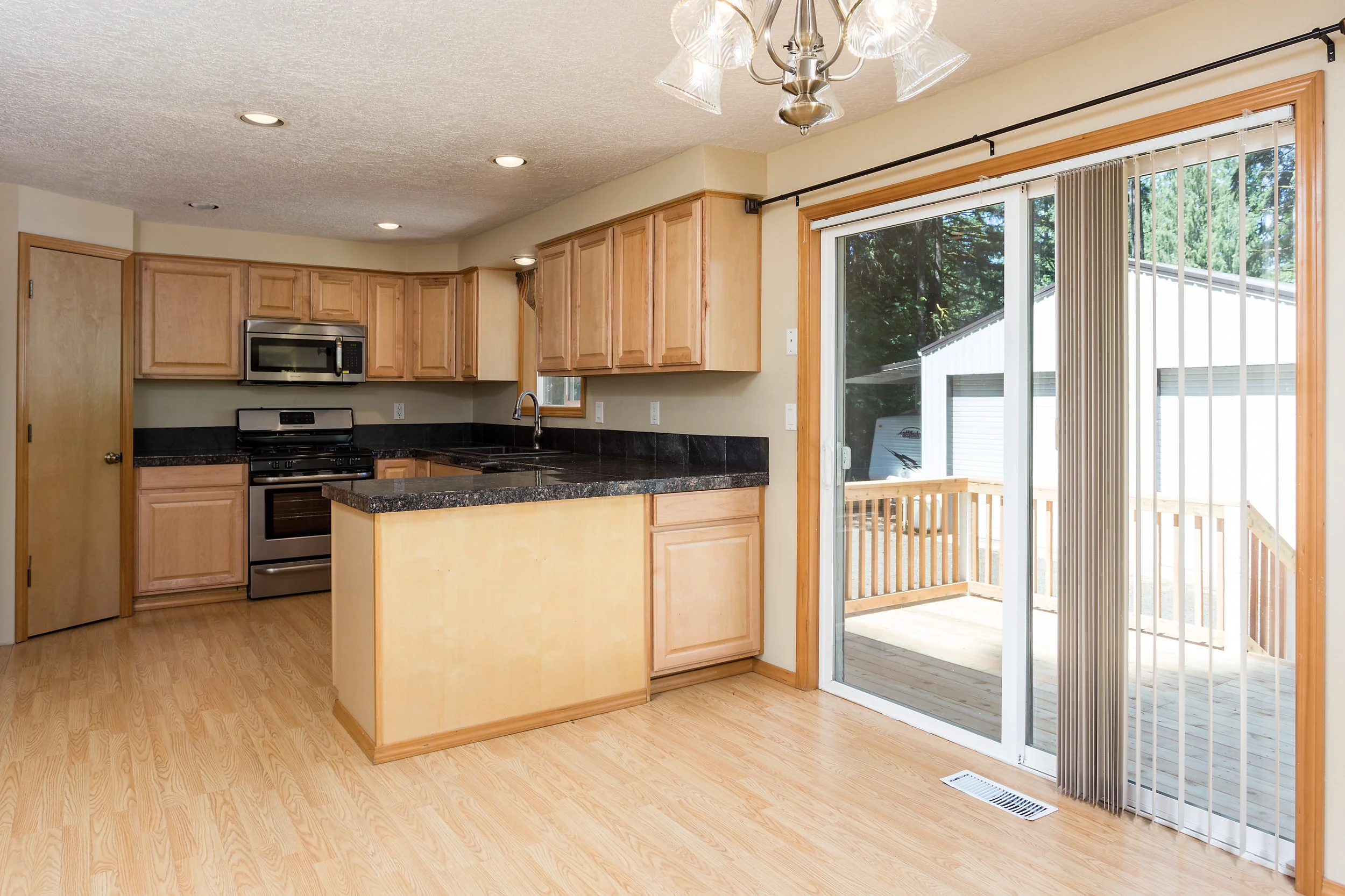 Kitchen with slider to deck overlooking large back yard with detached shop.