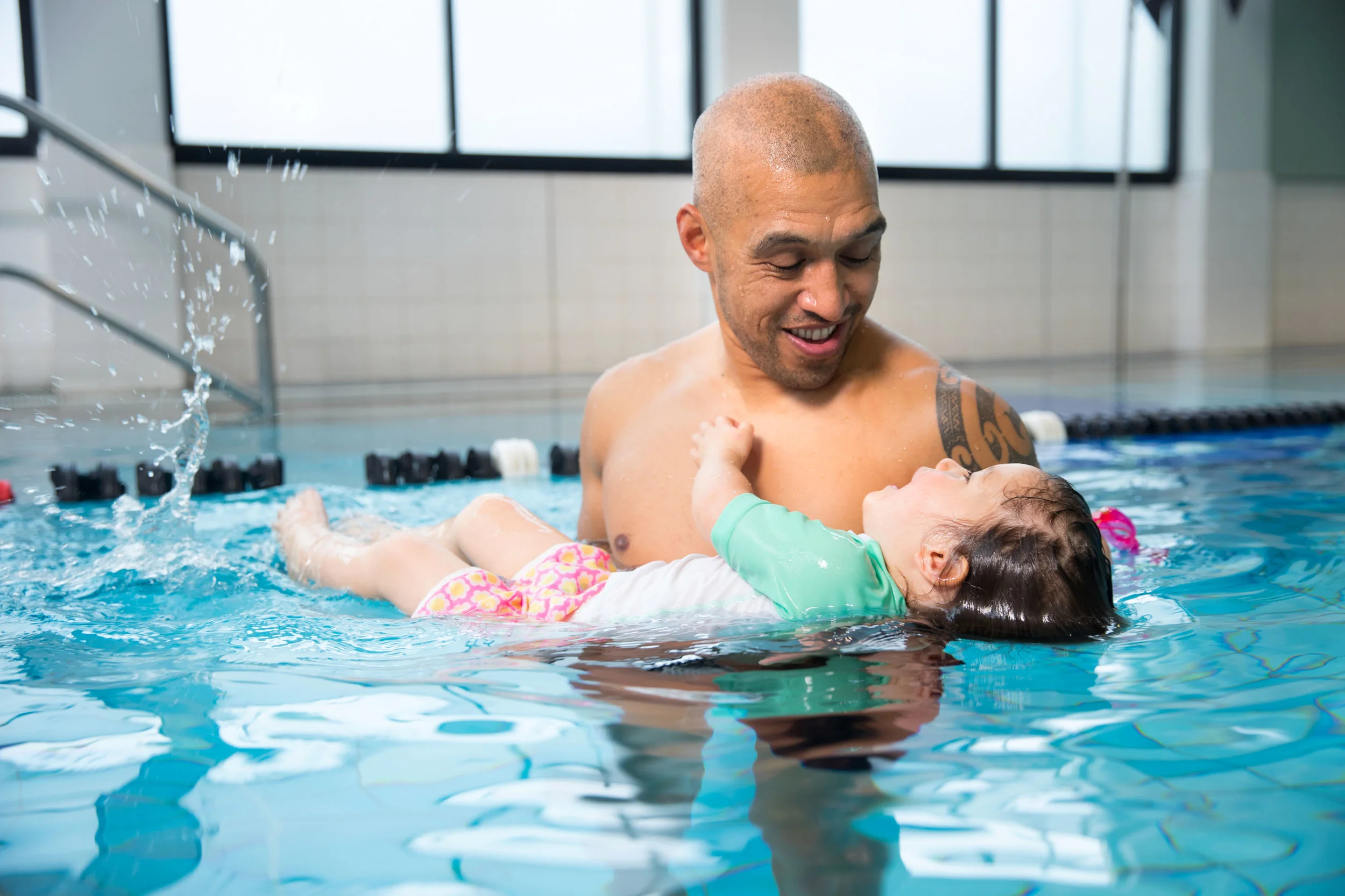 Pre-school child in the pool with her father.