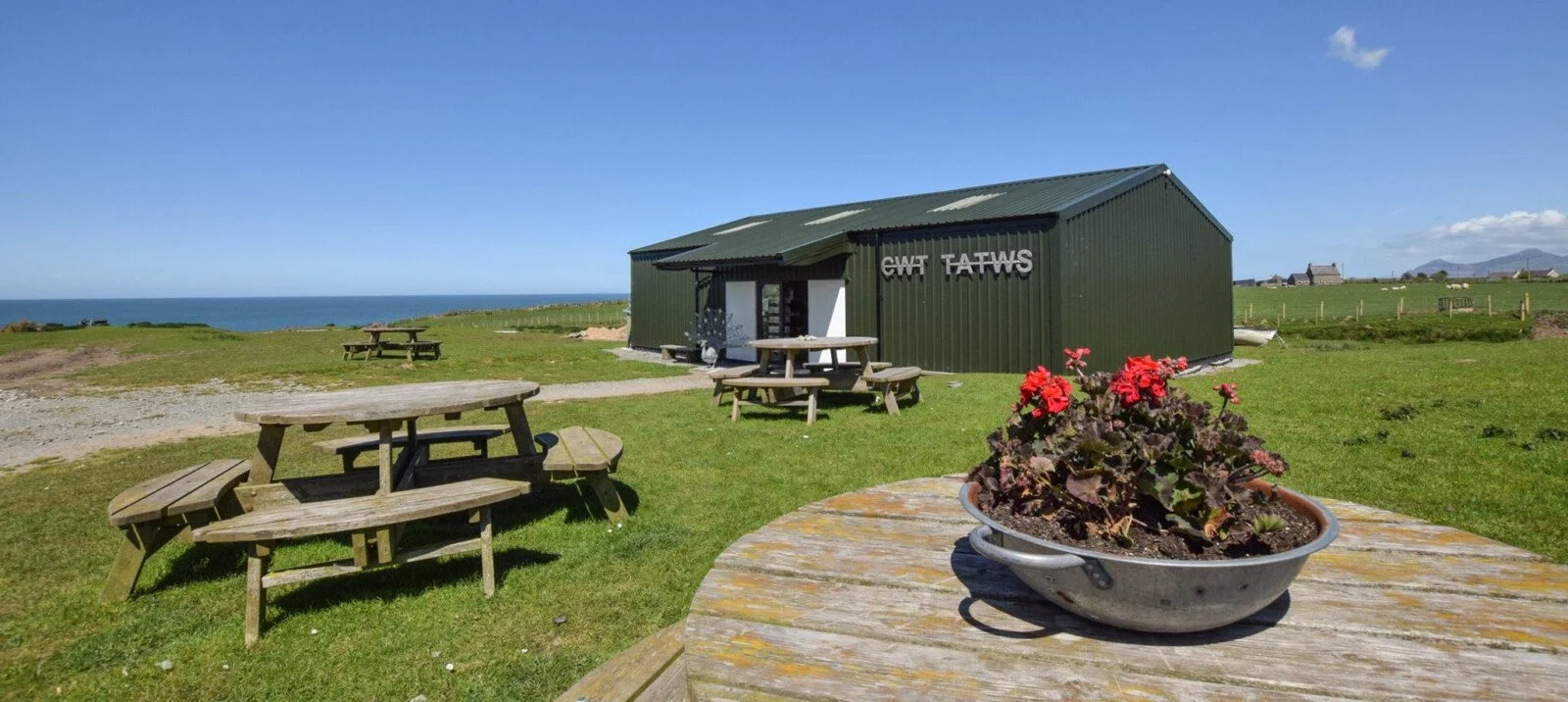 A photograph of CWT TATWS our lifestyle store and cafe in Tudweiliog with panoramic views of the sea in the background.