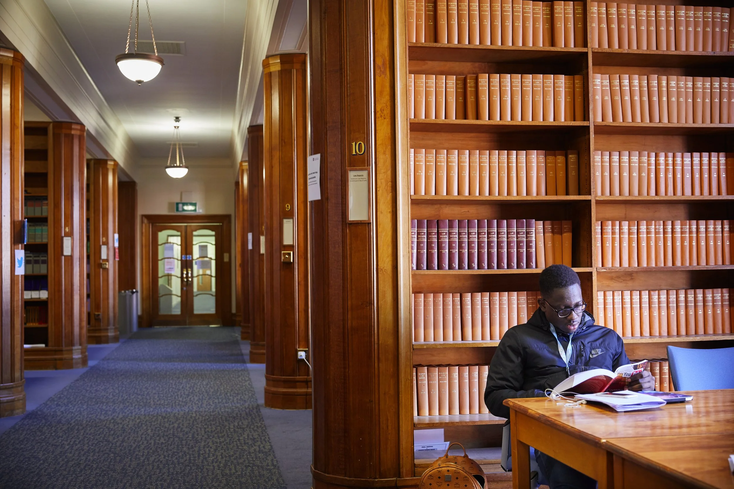 The harry Peach Library at the University of Leicester with wood-panelled bookshelves and a person sitting at a table reading.