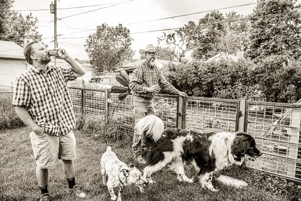 Men drinking beer, hanging out with dogs.