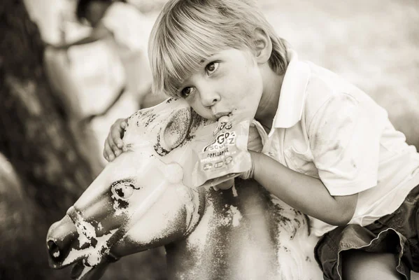 Closeup of little boy on plastic horse drinking a juice box.