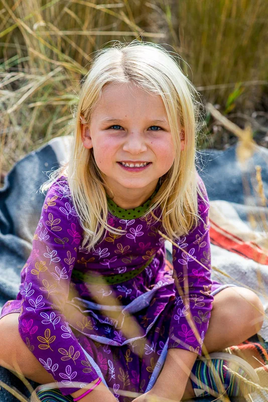 Cute little girl in purple dress in fall grass.