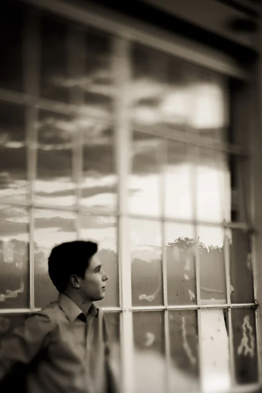 Artistic senior guy photo next to windows