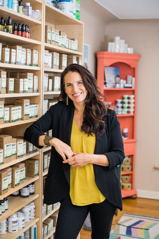 Lyric Turner in front of a wall of supplements in the Paramount Wellness office.