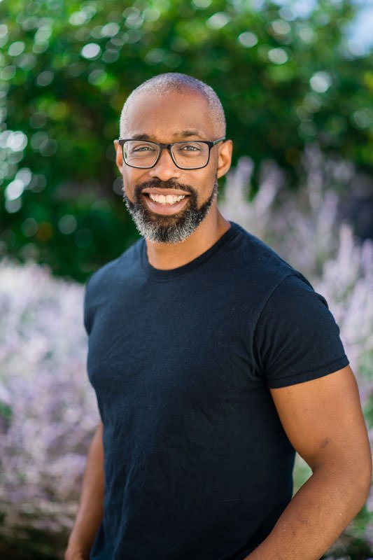 Arden Lewis, executive Chef and program manager for Focus Points nonprofit, in outdoor headshot at their office in front of purple flowers