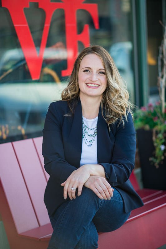 Financial advisor Melissa Thompson on a bench in front of a shop in downtown Castle Rock