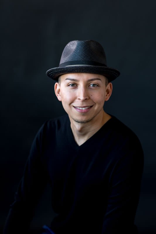 Studio headshots for realtor wearing black sweater and porkpie hat