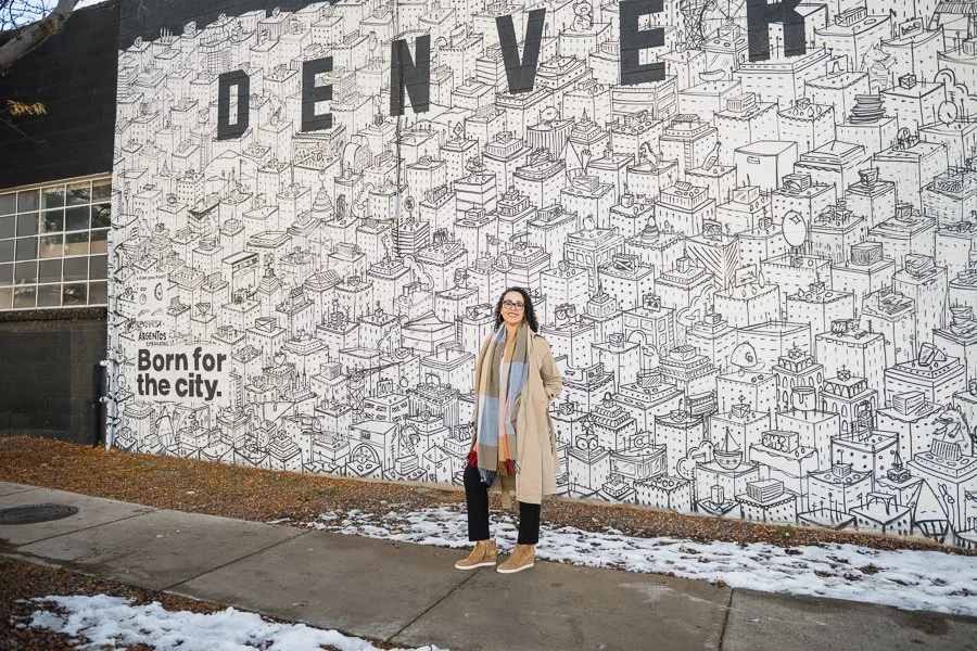 Cherri McKinney in front of a mural wall that says Denver  in RiNo