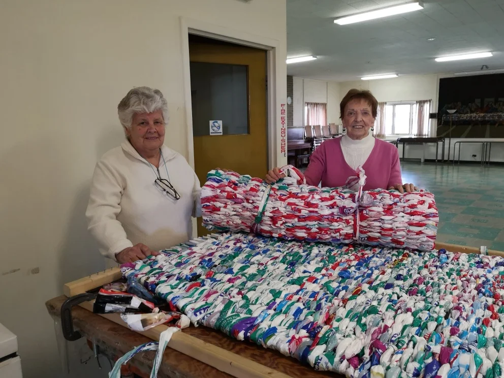 Two Summerlea volunteers with a milk bag mattress.