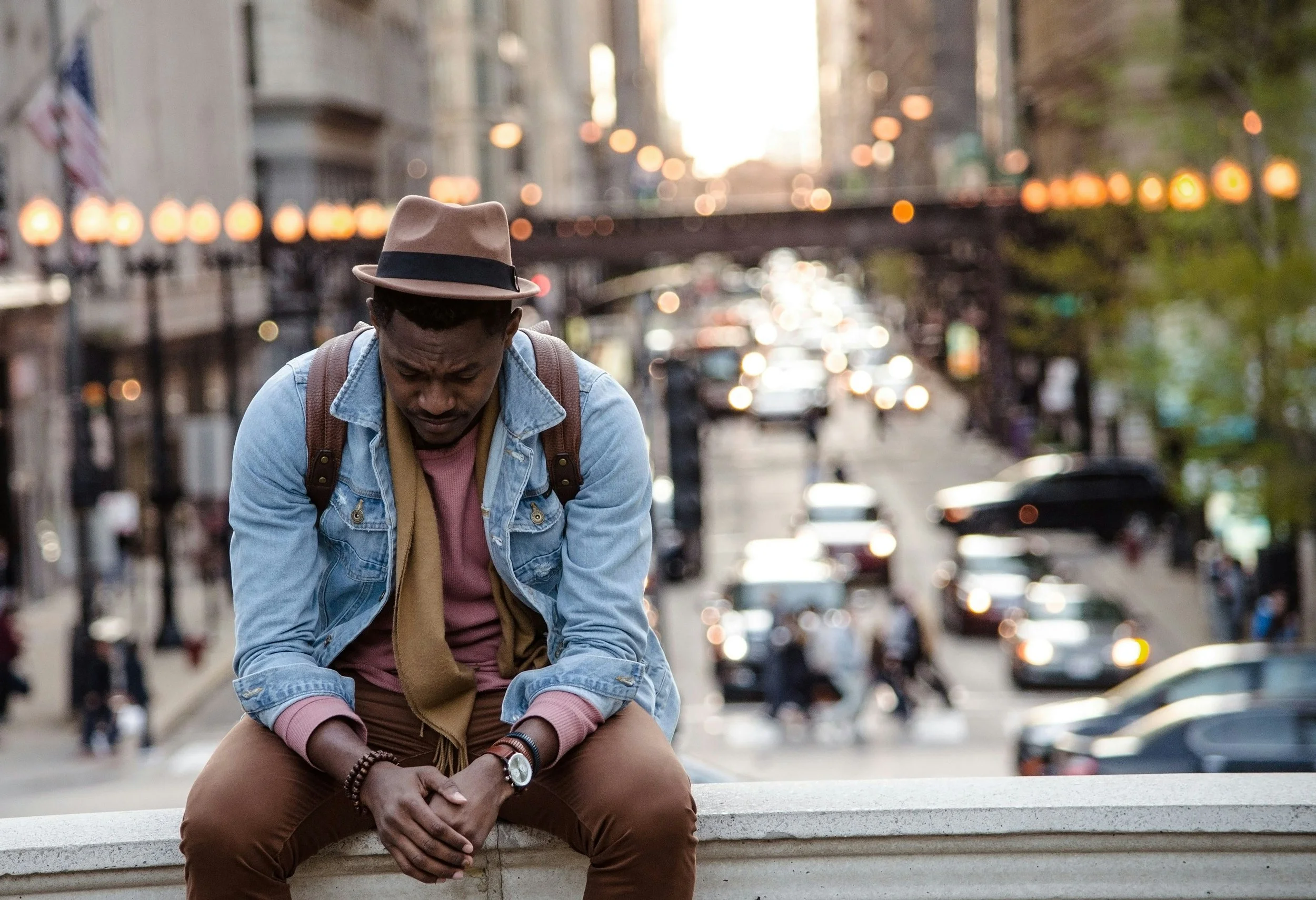 A gentleman sitting with a blurred city background behind him