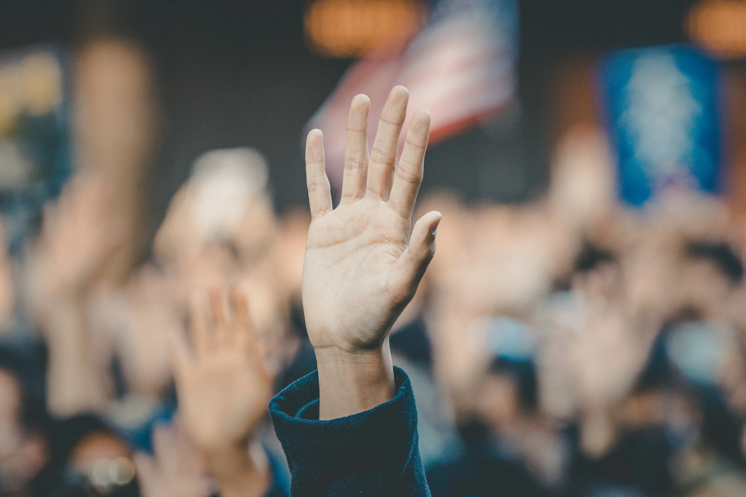 a hand raised with a blurred crowd in the background
