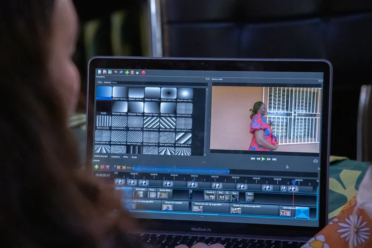 A local editor cuts footage on a laptop, preparing a community video for screening.