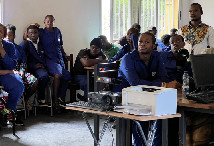 A classroom audience watches a video screening powered by a portable projector kit.