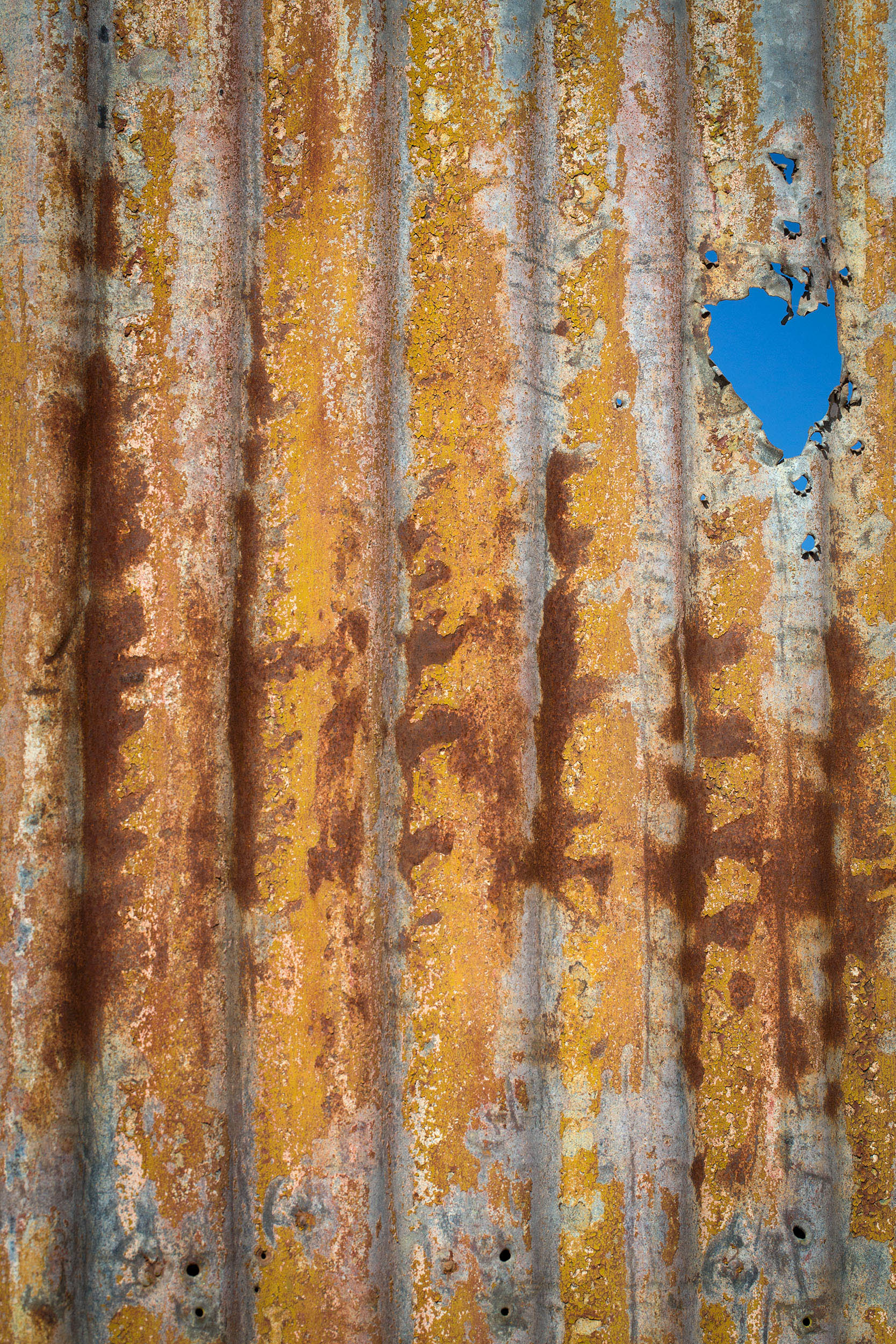 A patch of blue sky peeks through a corrugated iron fence at a closed mine, Broken Hill, NSW.