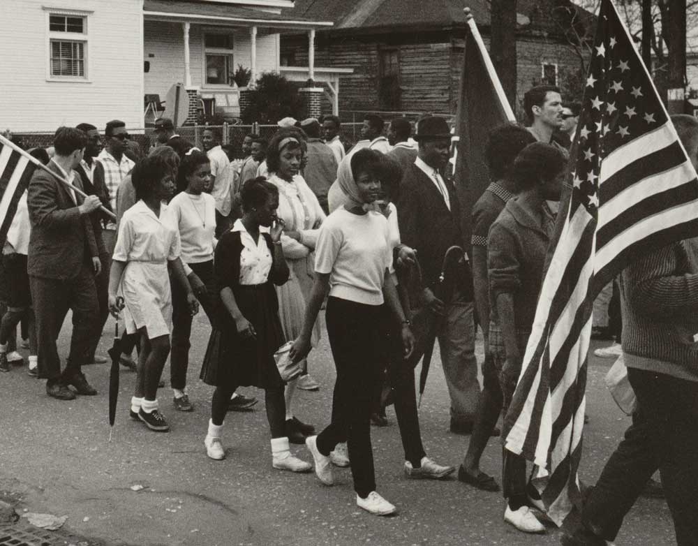 Participants, some carrying American flags, marching in the civil rights march from Selma to Montgomery, Alabama in 1965. Photo by Peter Pettus