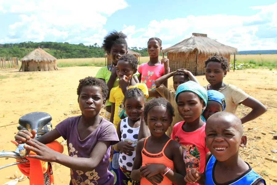 Above: With meat being sold to towns, women and children subsist on cassava cakes, which are not enough to sustain them but are the main crops resilient to the nutrient-deficient soils in the Okavango Wilderness Project study area. Below: Luchaze children. Photos: Chris Boyes