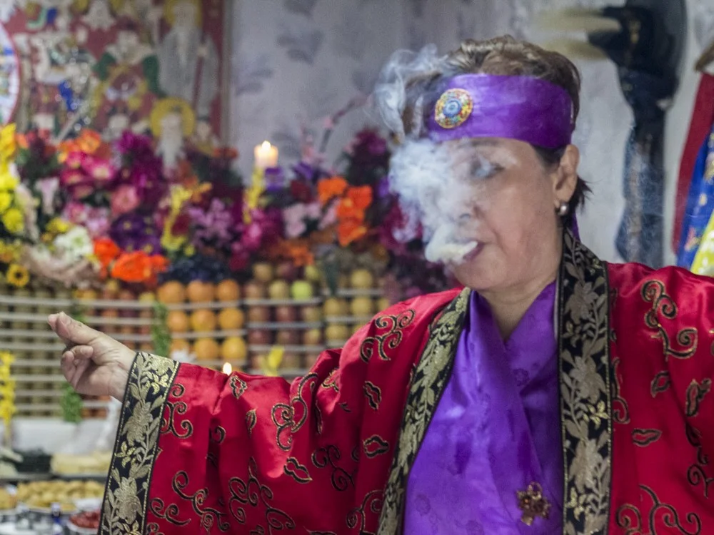 A Chinese Envoy of Death God appears at a shamanic ritual in a dedicated ritual space called a gutdang, near Kookmin University, Seoul. This particular female god enjoys heavy drinking and smoking, demanding to be pleased in order to placate her anger. The ritual was carried out by manshin Kim Nam-Sum.