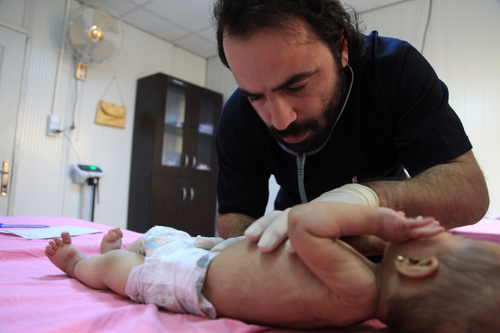 Dr Hatem, the medical director of Hope Hospital, examines a baby for signs of dehydration and malnutrition.