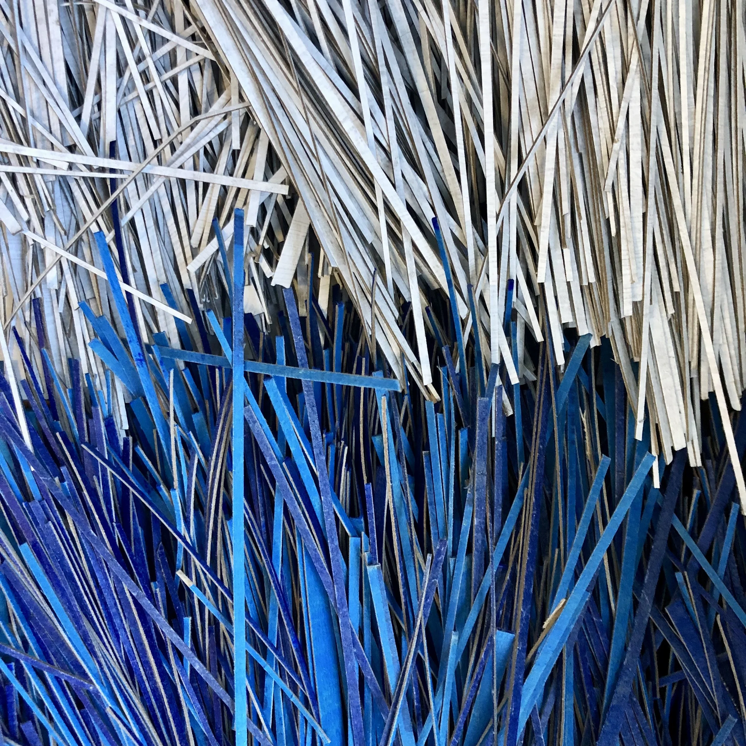 The compressed paper works begin with prepping thousands of strands of painted strips.  