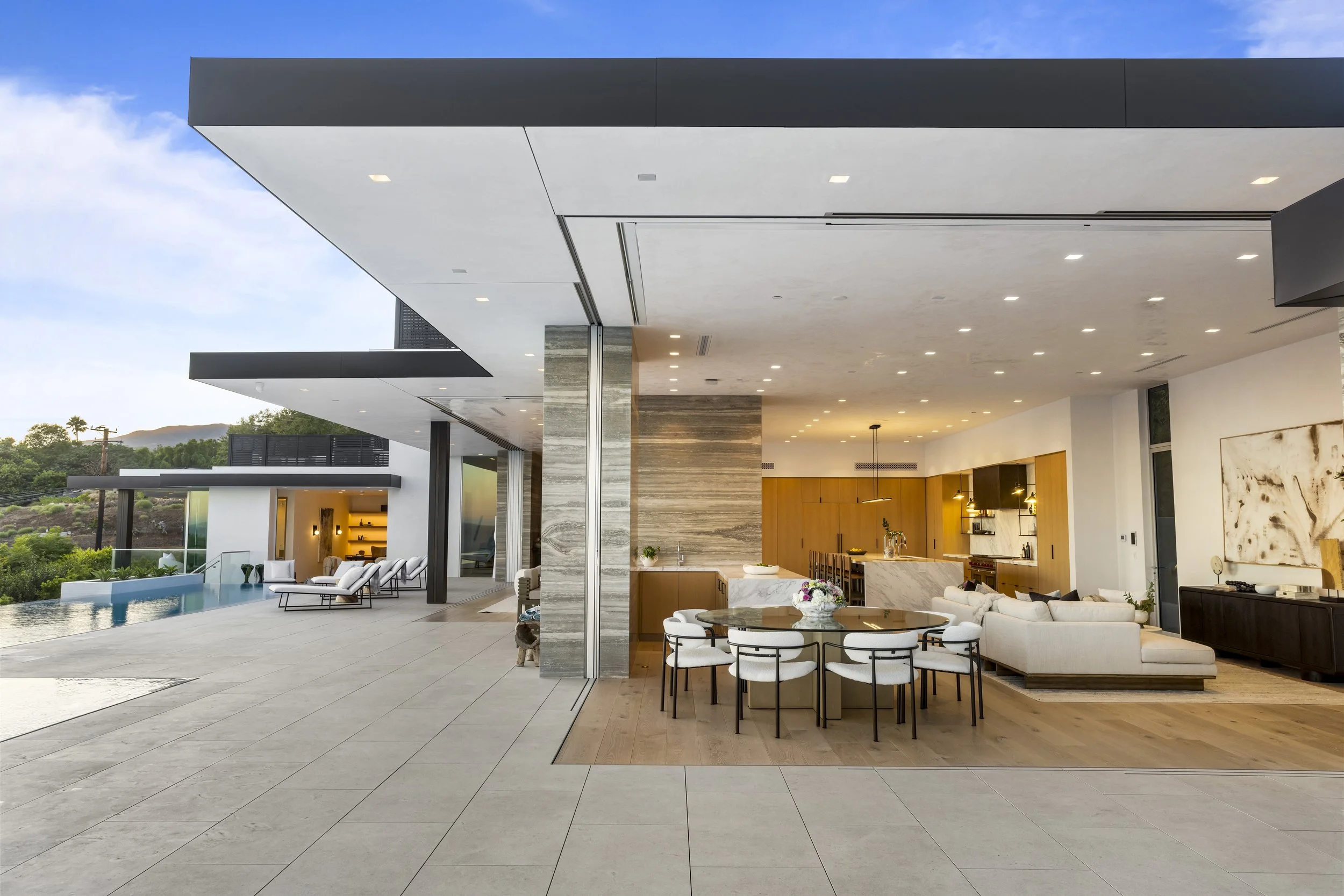 Modern open-concept living space with view of outdoor patio, pool, and landscape.