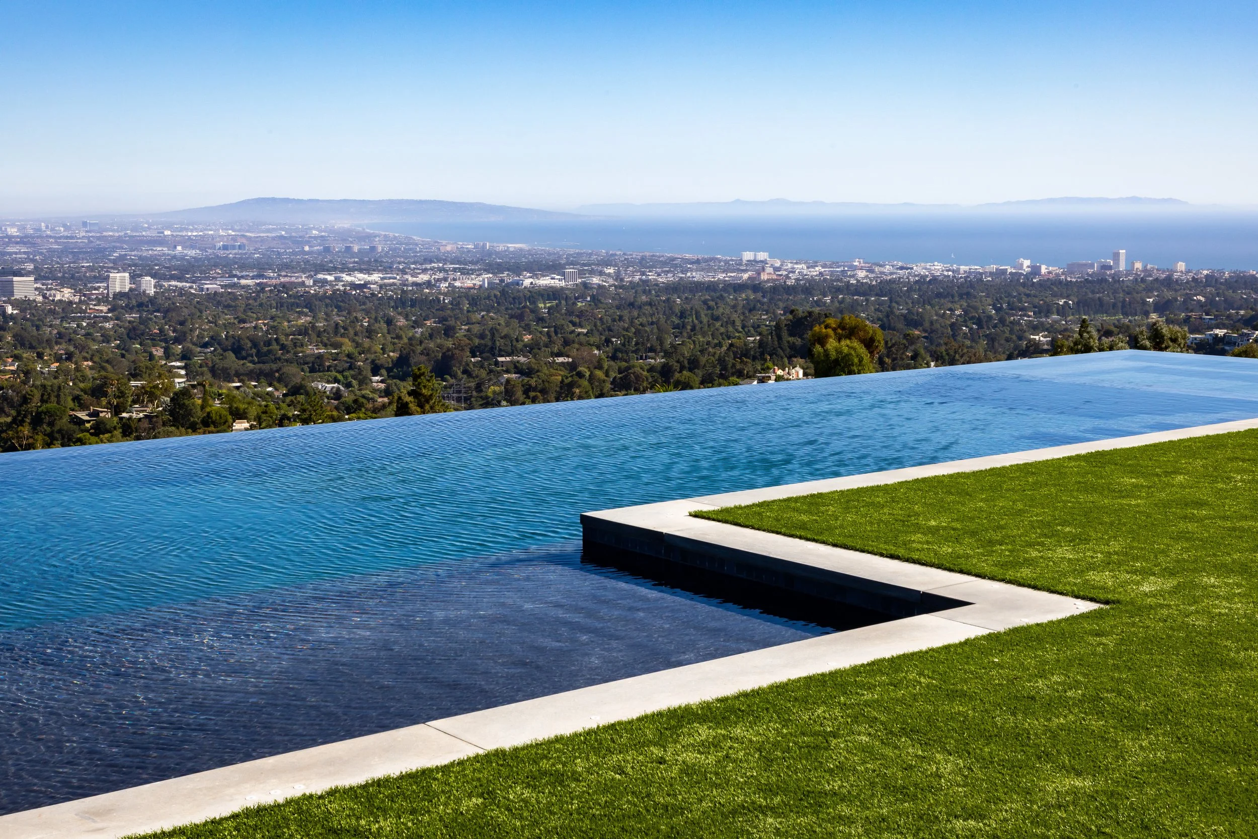 Infinity pool with cityscape and ocean view in the distance.