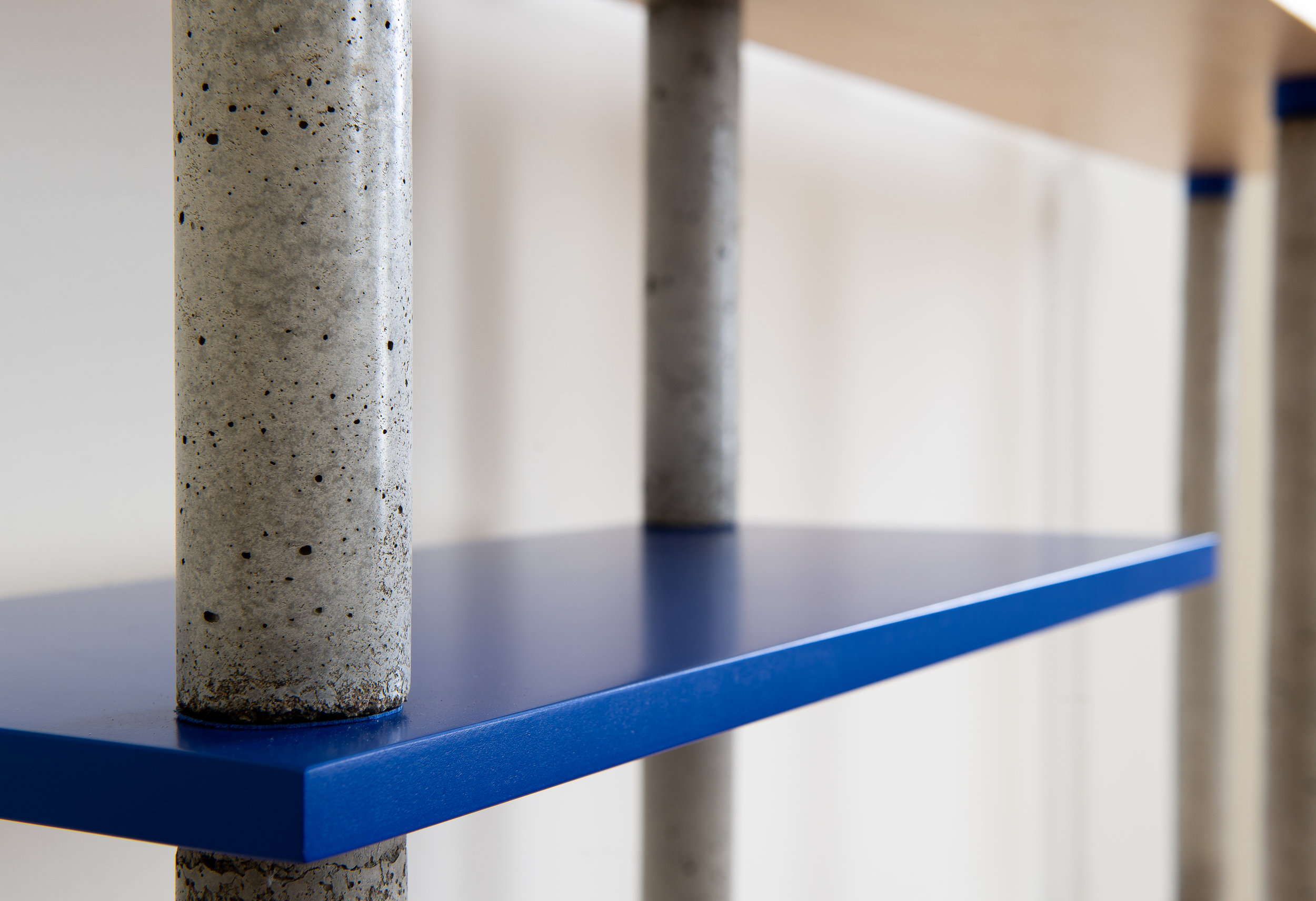 Concrete bookcase pillars with cobalt blue shelf