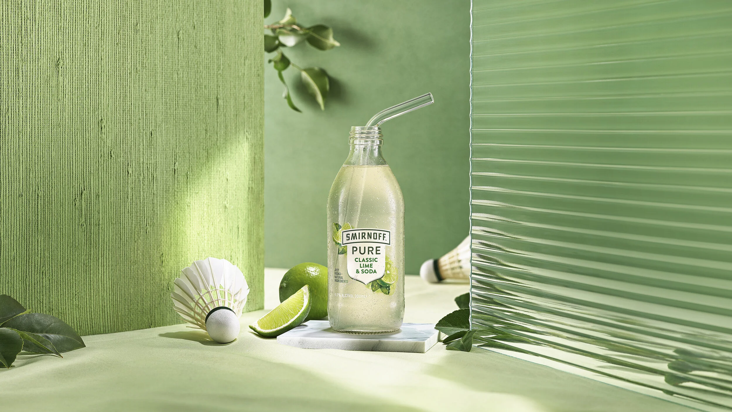  Advertising image for Smirnoff Pure Lime and Soda, sitting on lime green set and fluted glass with shuttlecock and lime leafs. Advertising beverage photographer. 