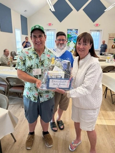  St John's Joe Beard (Left) presents a winning StB EpiscoGolf Gift Basket to a lucky BBQ guest  &amp; golfer, Elaine (Right) of East Wakefield, as StJB Parson Kit peeks out from behind. 