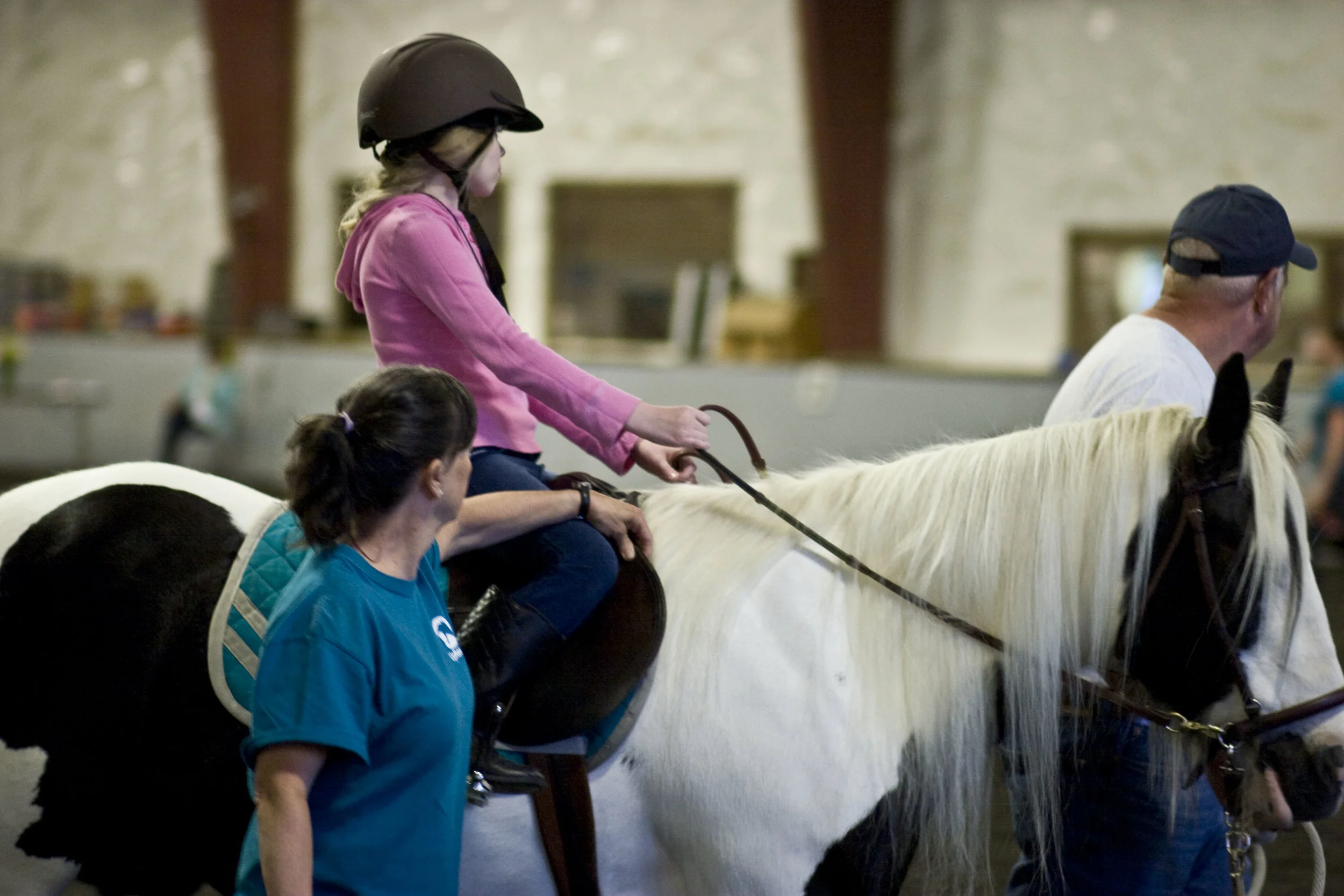 Side walker, Colleen, provides support to a therapeutic riding participant.