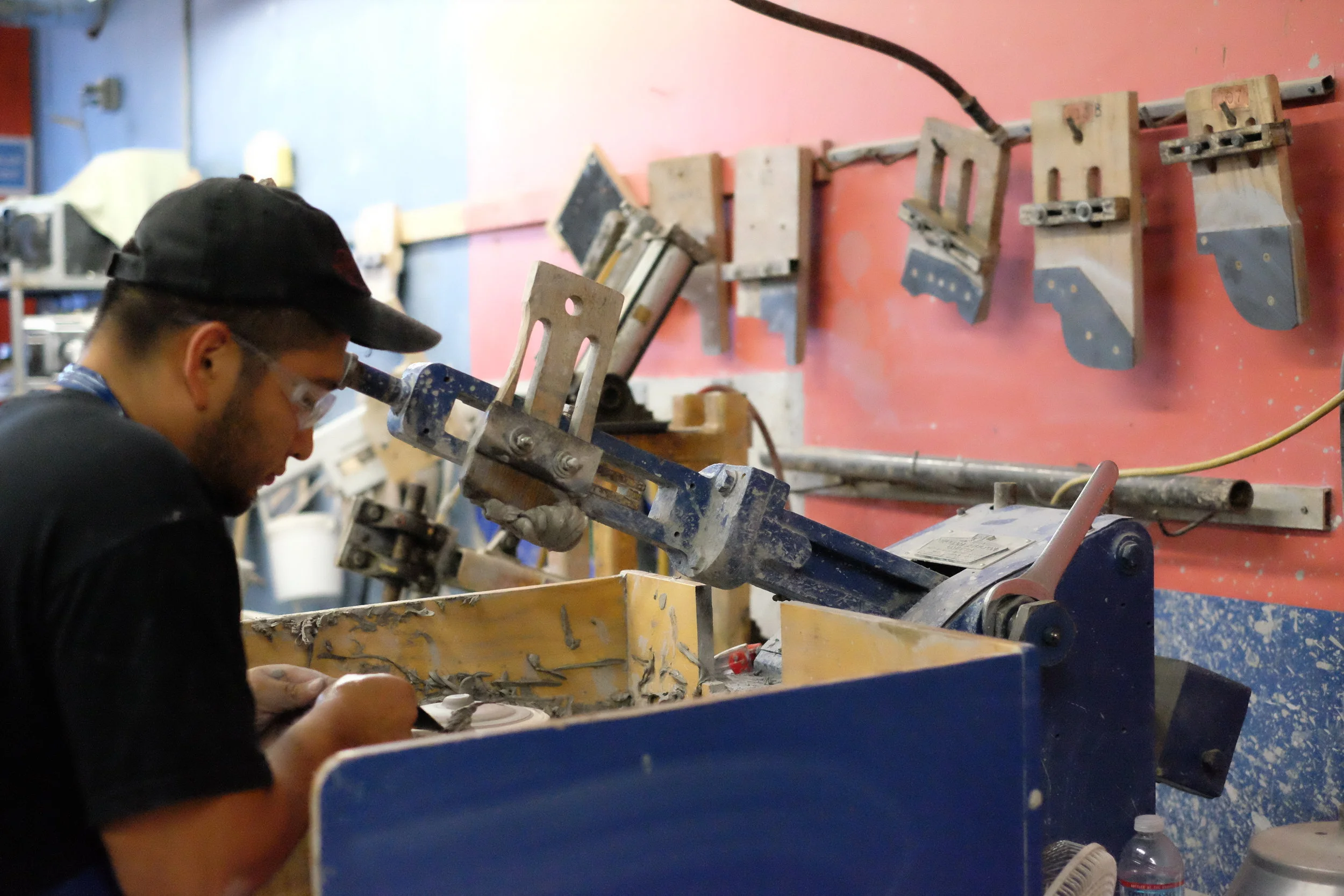 A Heath craftsman throws jar lids assisted by a jigger (that arm thing).