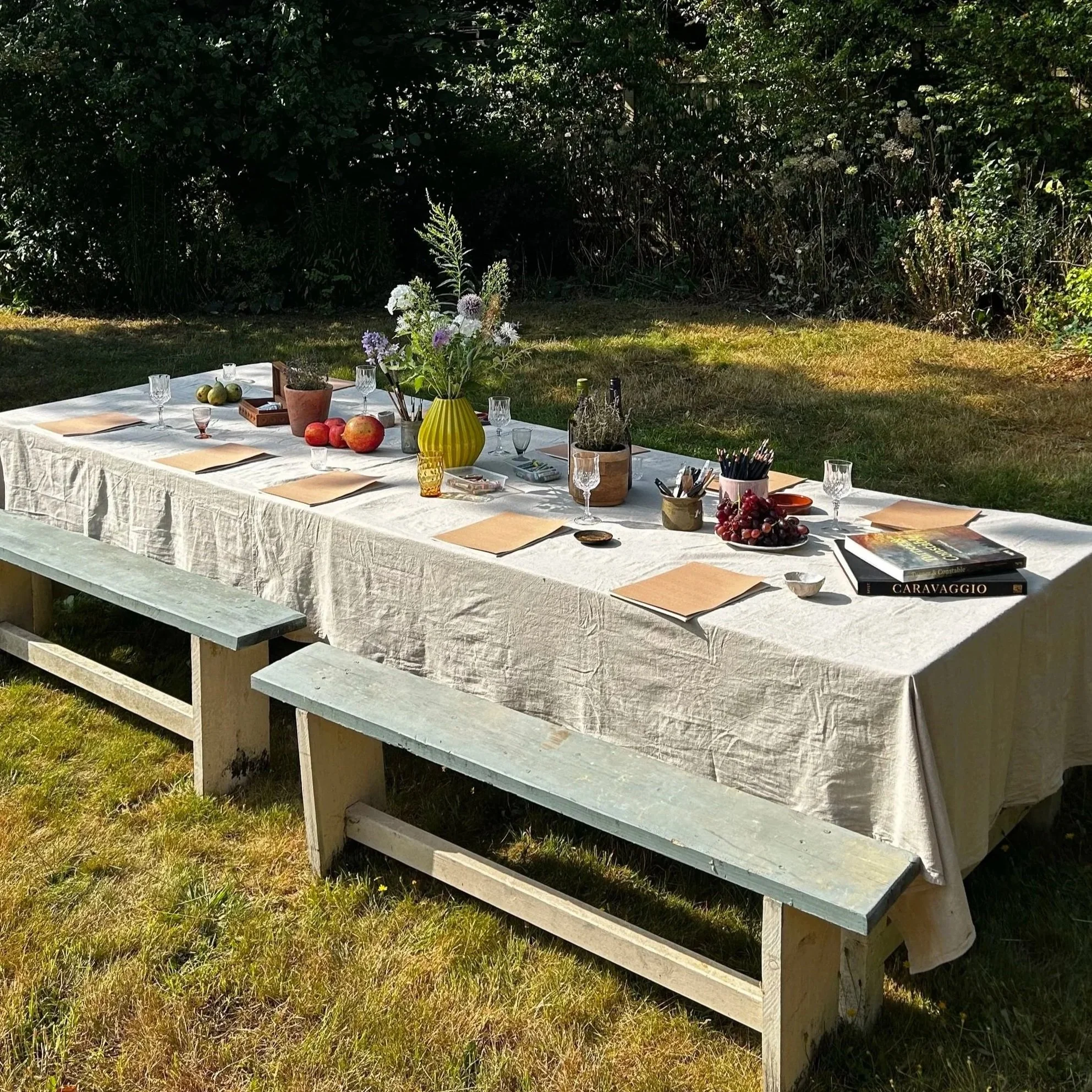 Large table laid out with art class materials and wine ready for an art workshop