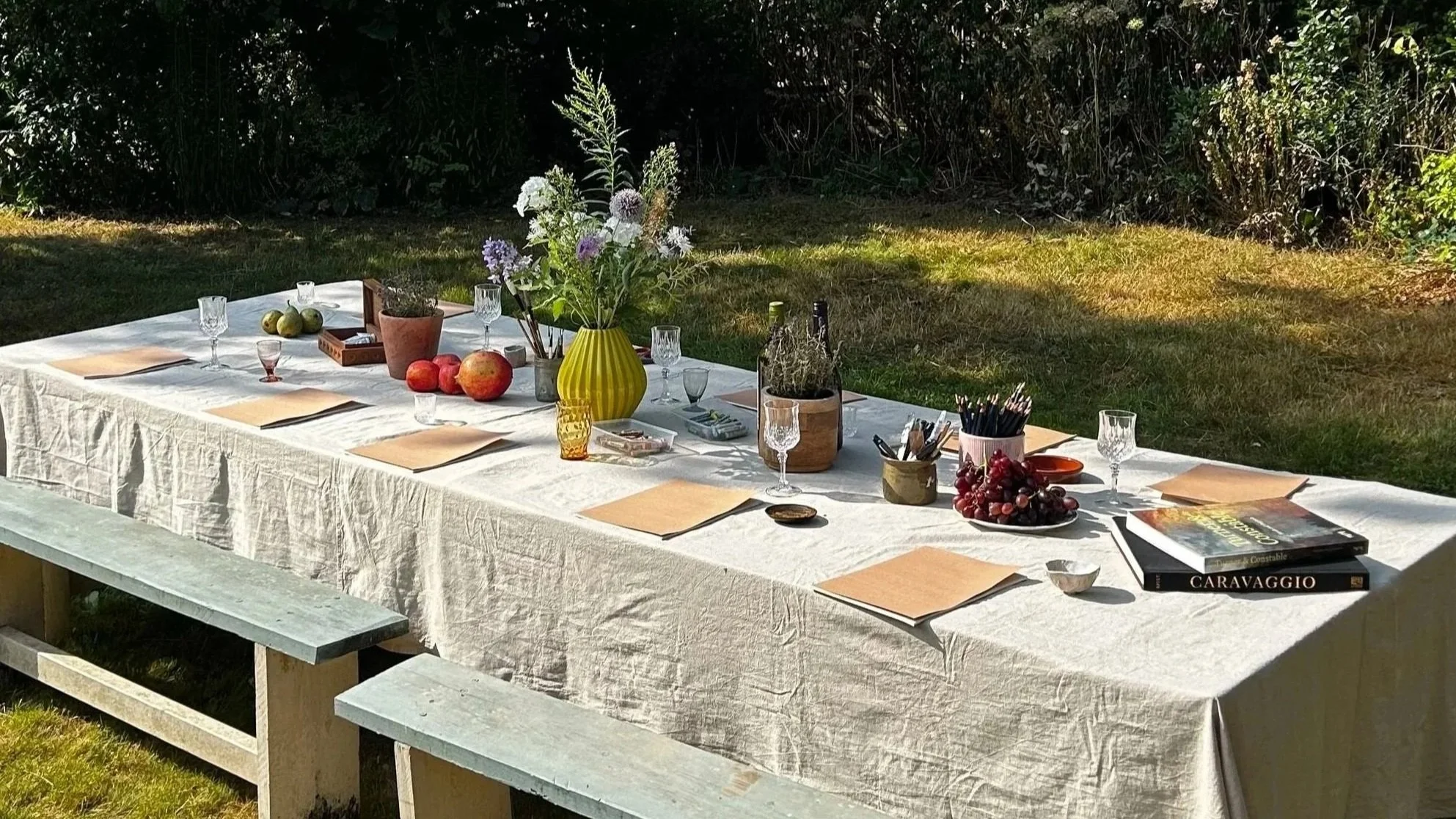 Table set with flowers, fruits, and art supplies, ready for an art class