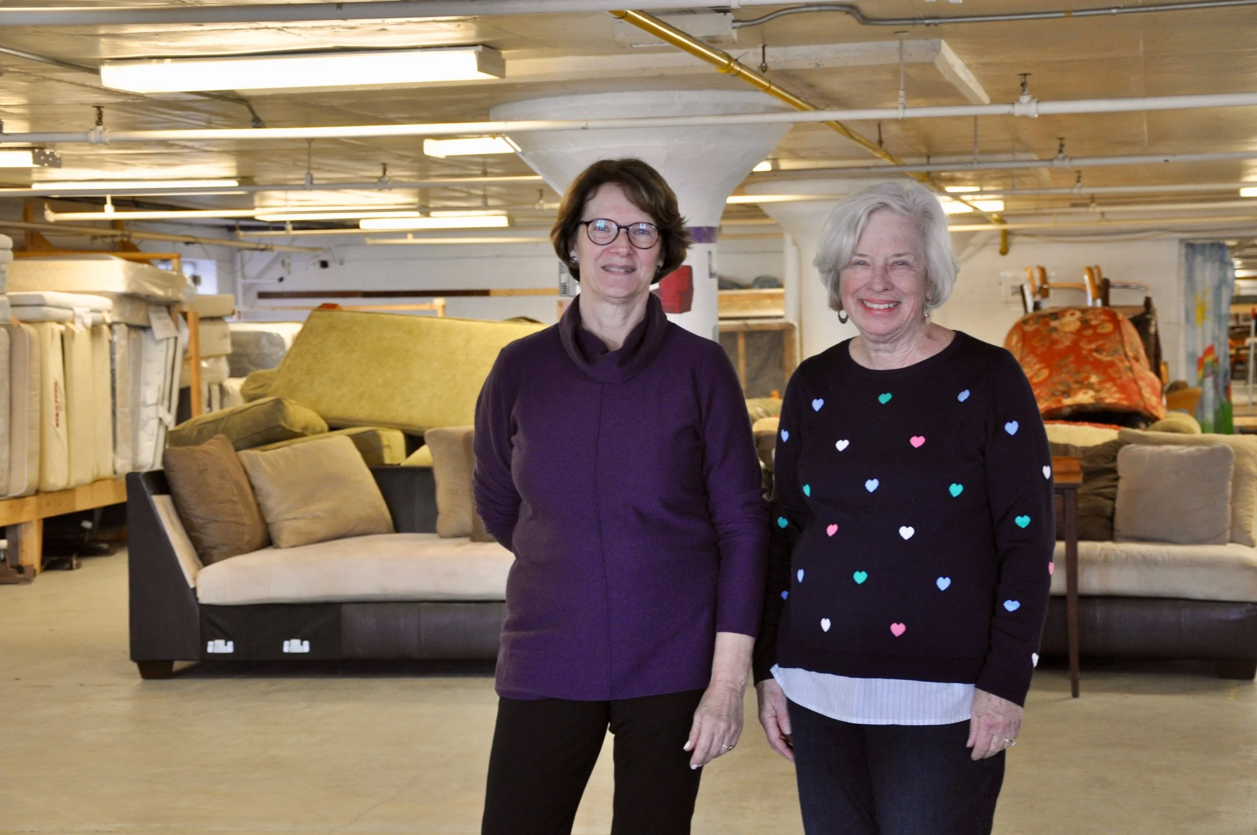 Volunteer Coordinator Laura Stanton and Founding Member Barbara Yates stand committed to helping families recover from homelessness, breaking down stereotypes and giving clients a warm, respectful experience at New Life’s distribution center.
