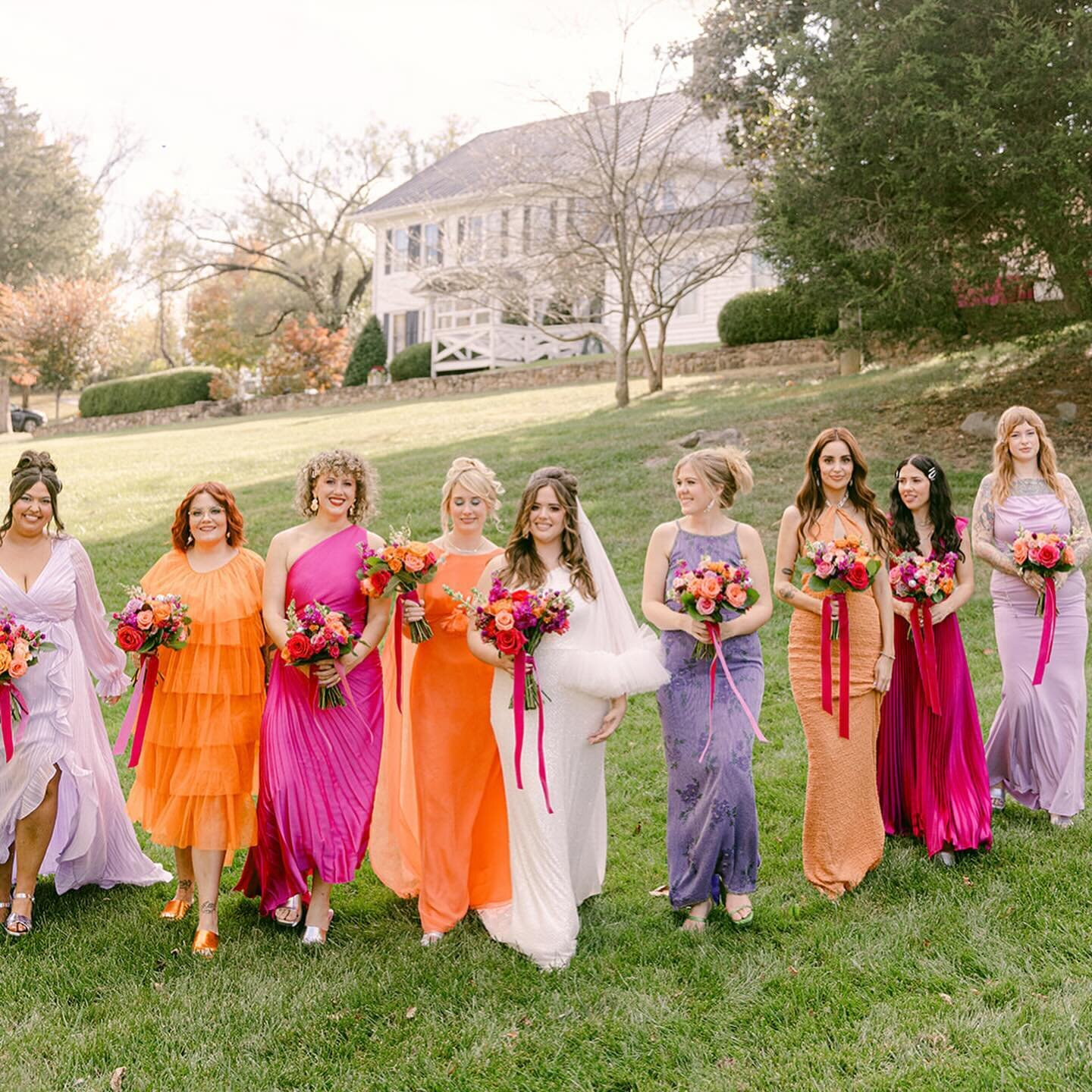 The bridal party color palette, adorned with vibrant pinks and oranges, creates a stunning visual symphony against the lush green backdrop of Sunnybrook&rsquo;s front lawn. The historic home serves as a timeless and picturesque setting, providing an 