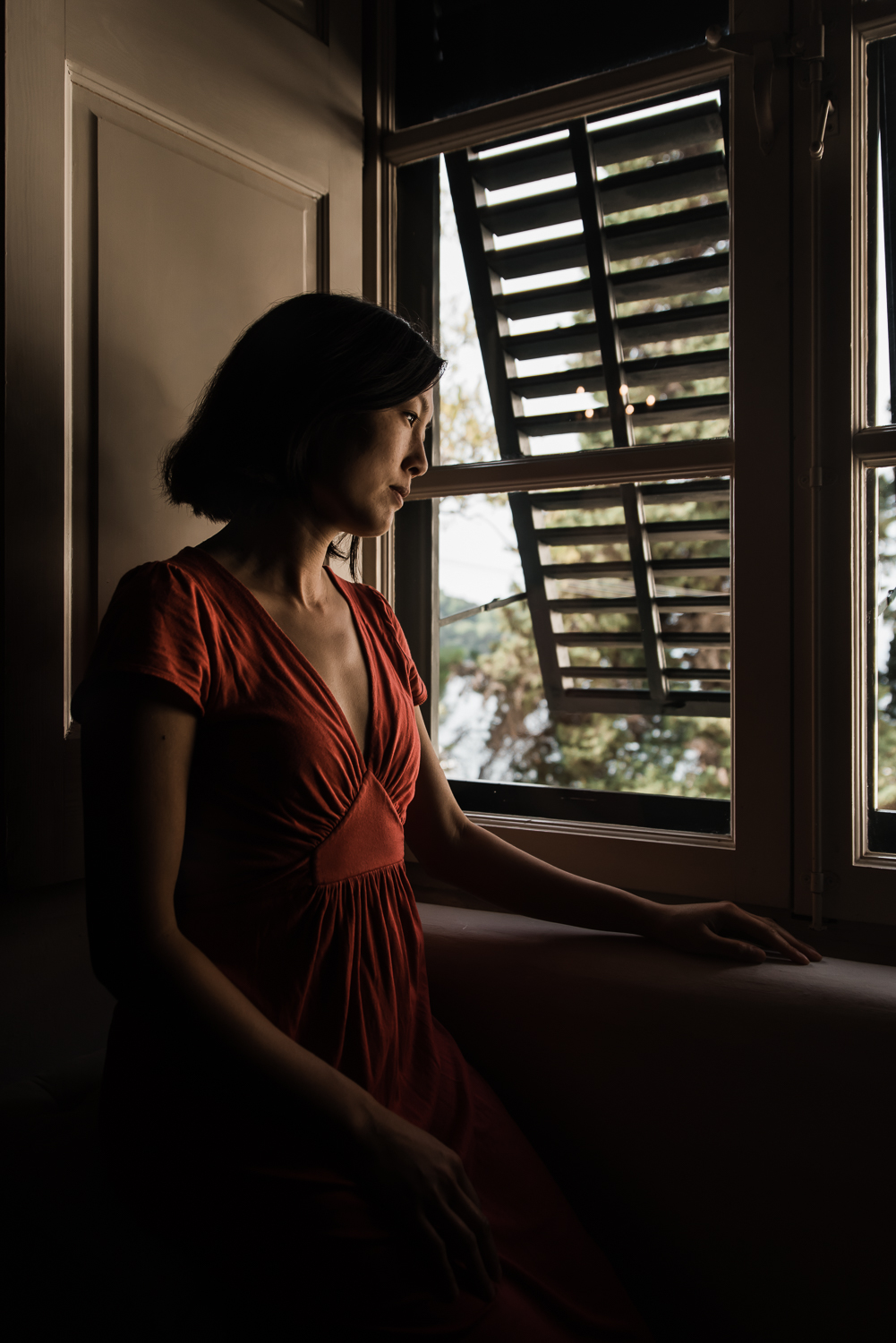  woman in red dress sitting by the window for dear photographer magazine 