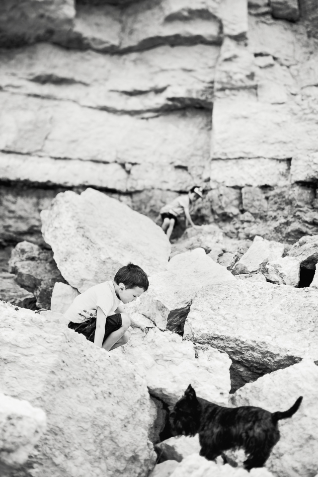 Children climbing rocks at Hunstanton cliffs in black and white 