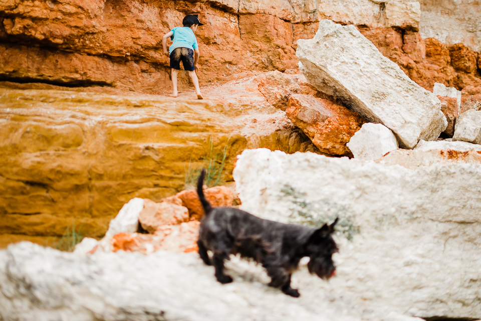 Boy and his dog climbing on the red and white sandstone rocks at