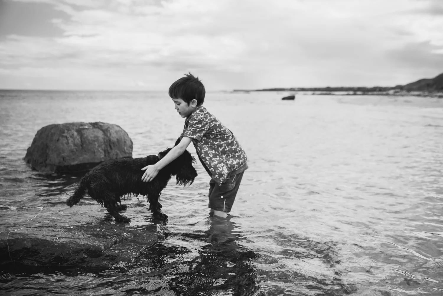 Black and white photograph of a boy and his dog in the sea