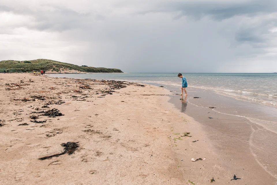 Child walking on the beach at Bamburgh