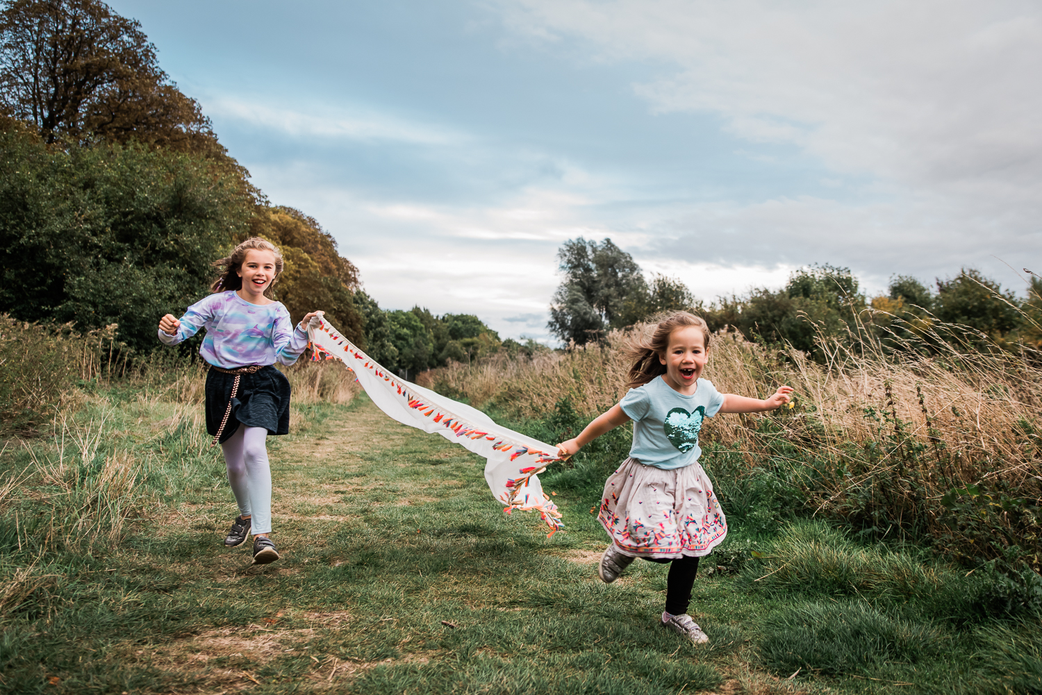 Children running with a colourful scarf down a grass path