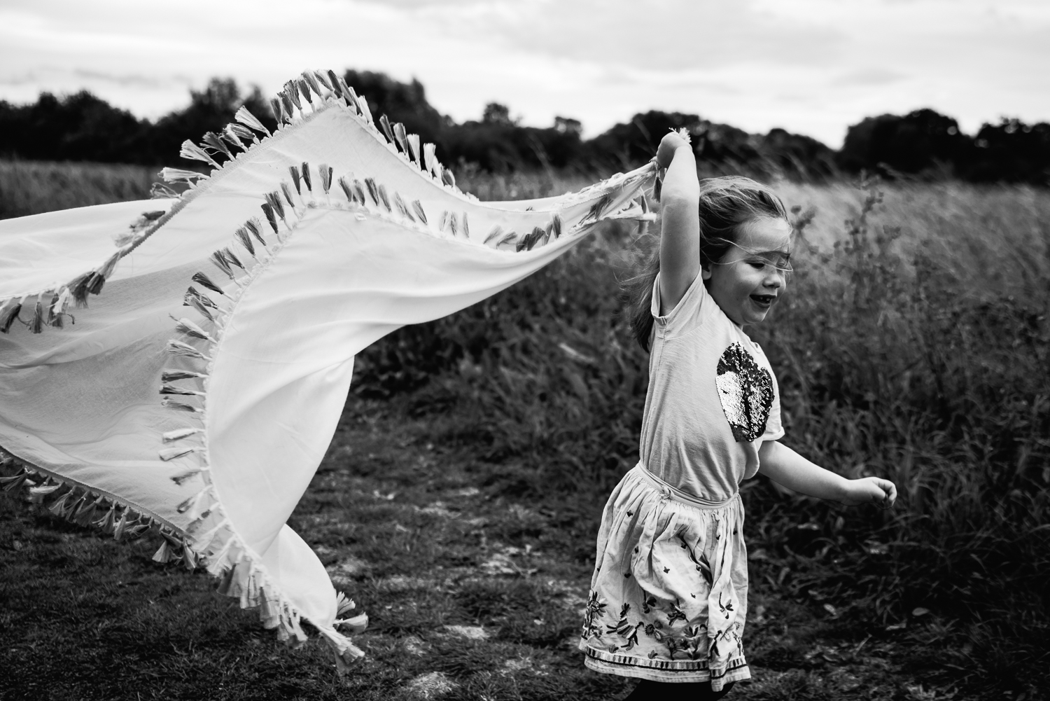 Black and white photograph of a girl running with a scarf in her