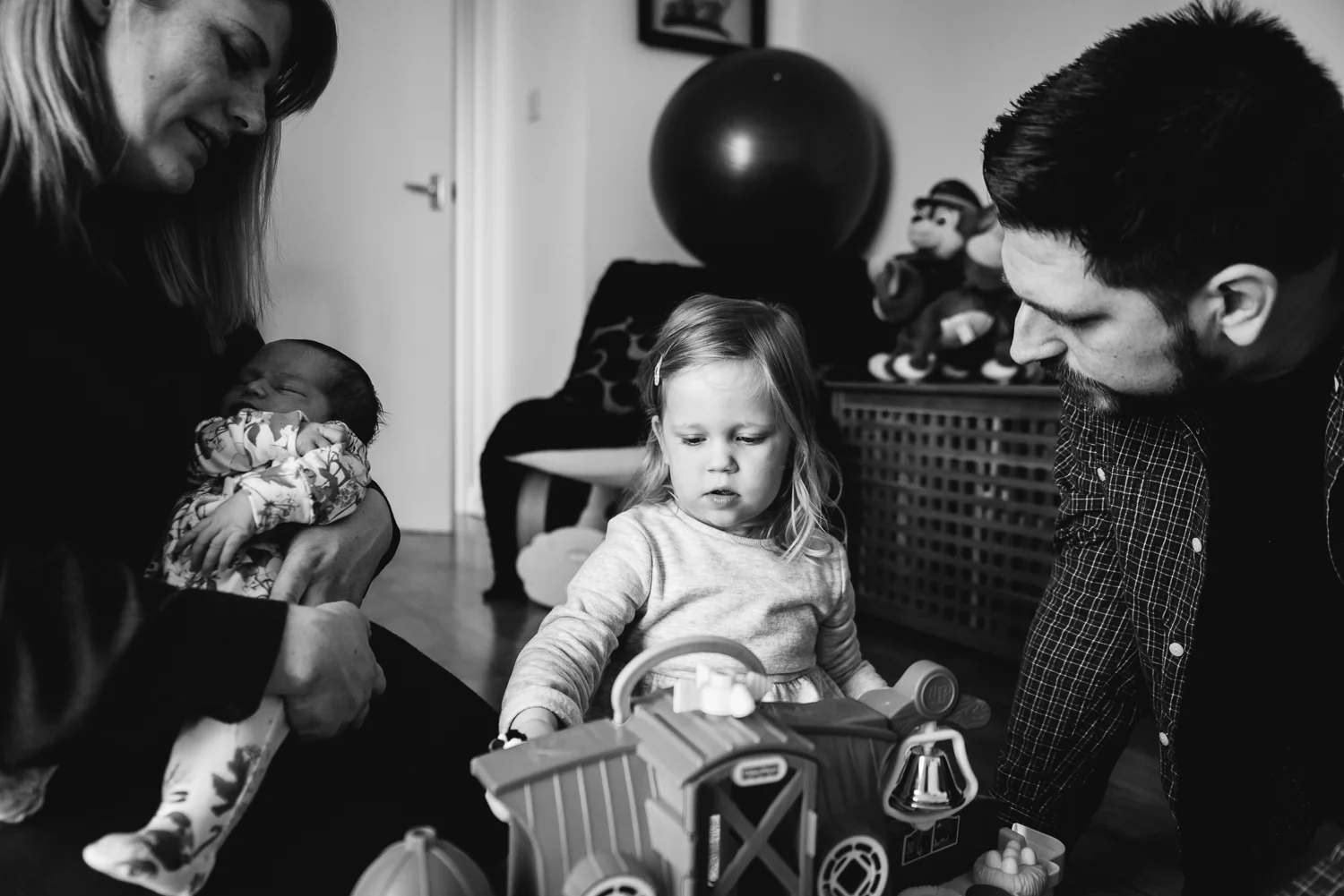 Black and white photograph of a young family of four sitting tog