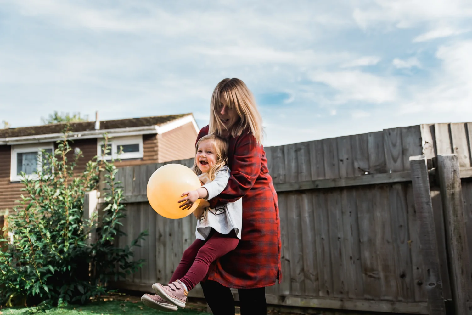 Mum and daughter playing with a ball outside in the garden on a