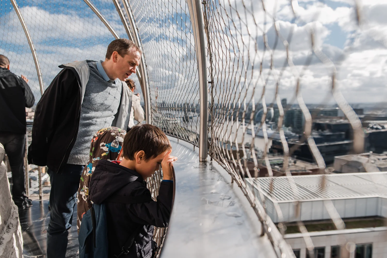 A father and son stands at the top of The Monument looking down