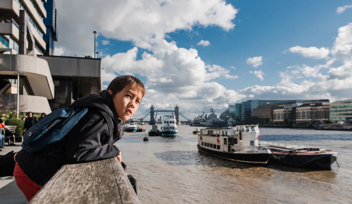 A photo of a boy leaning over the side by the river Thames with