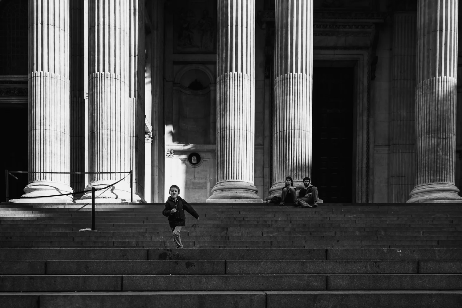 Boy running down the steps of St Paul's cathedral black and whit