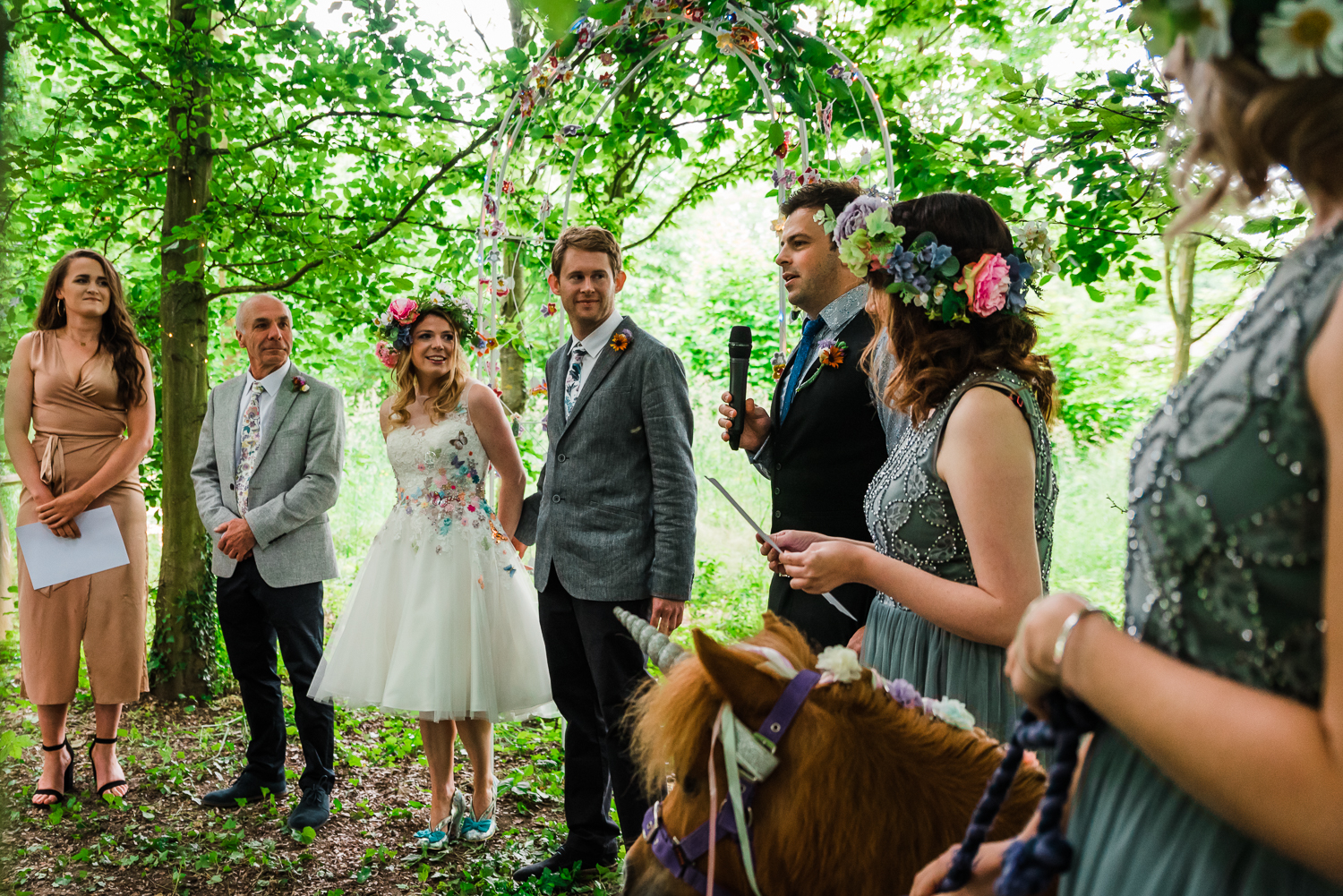 The wedding party standing in the woodland of the outdoor weddin