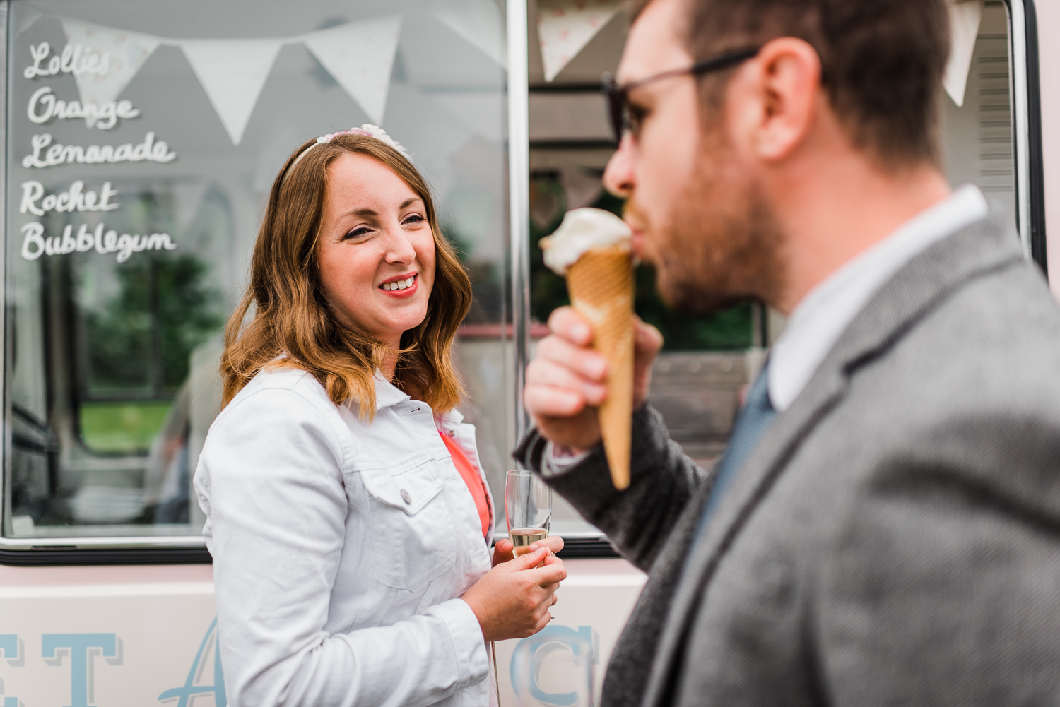 Male guest eating ice-cream while a woman watches on at a festiv