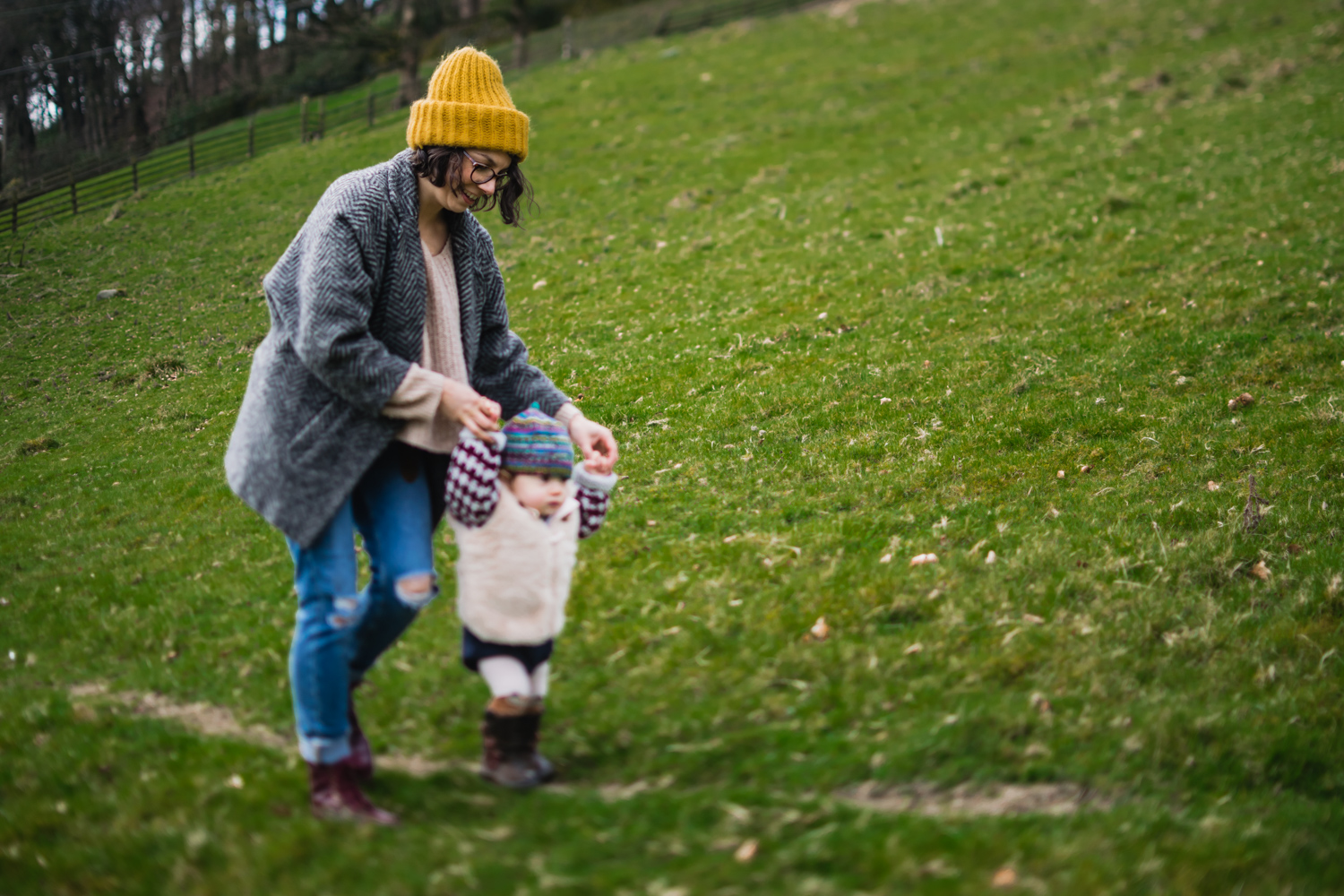 Copy of A mother walks with her toddler while holding onto her hand on t